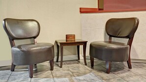 Two leather chairs with wooden legs and a small wooden table between them.