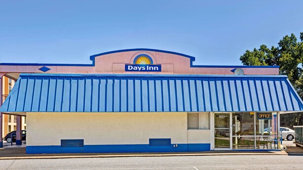 A Days Inn with a blue awning, a visible office entrance, and a parking lot.