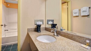 A bathroom with a sink, mirror, towel rack, and a shower.
