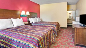 A hotel room with two beds, a desk with a TV, and a bathroom visible in the background.