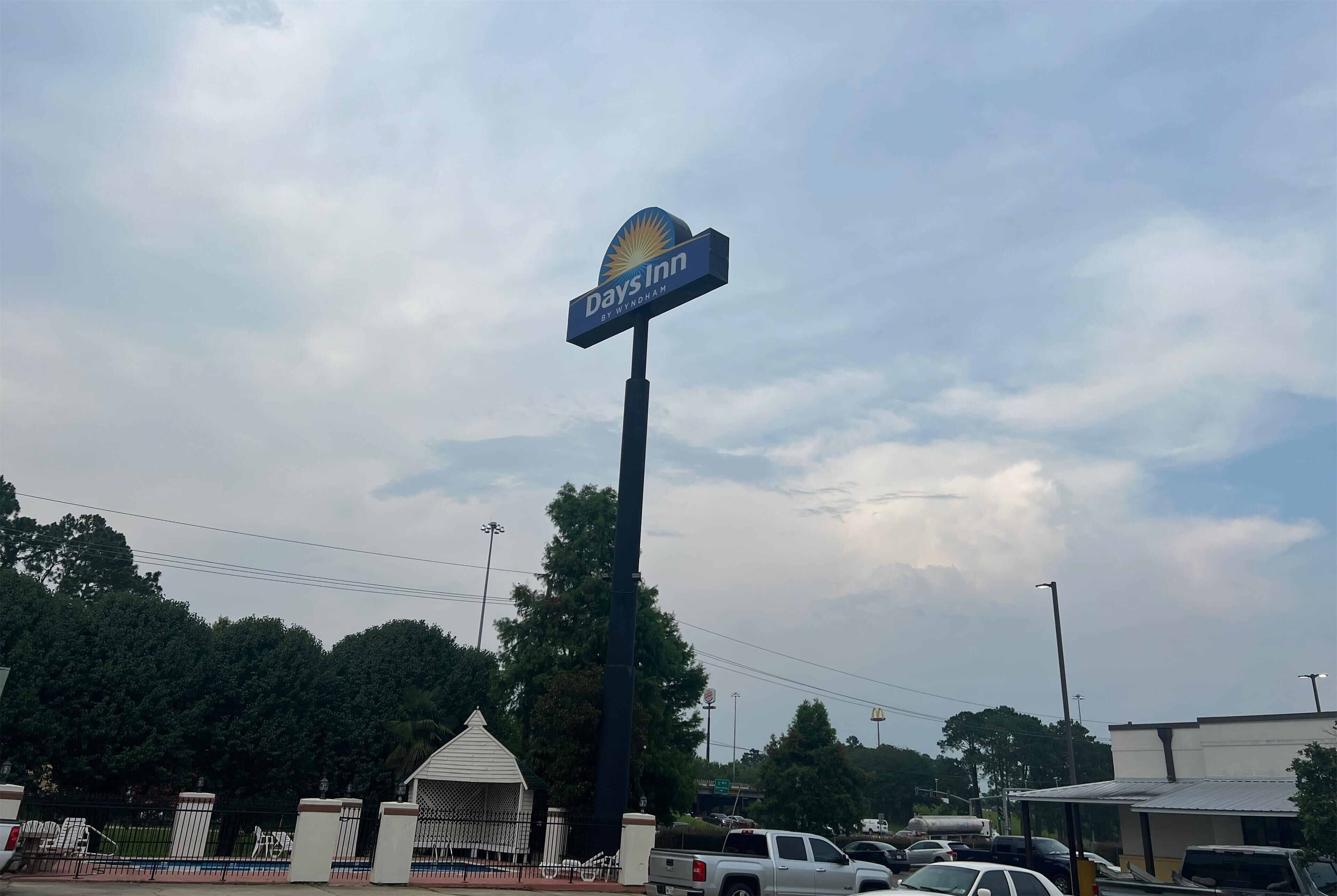 Señal de Days Inn, con una vista clara del área de estacionamiento circundante y una entrada con portón.