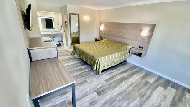 Habitació d'hotel moderna amb llit, taula de nit i un petit escriptori amb mirall.