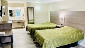 Habitació d'hotel amb dos llits individuals, una taula de treball, un mirall, una finestra i un bany.