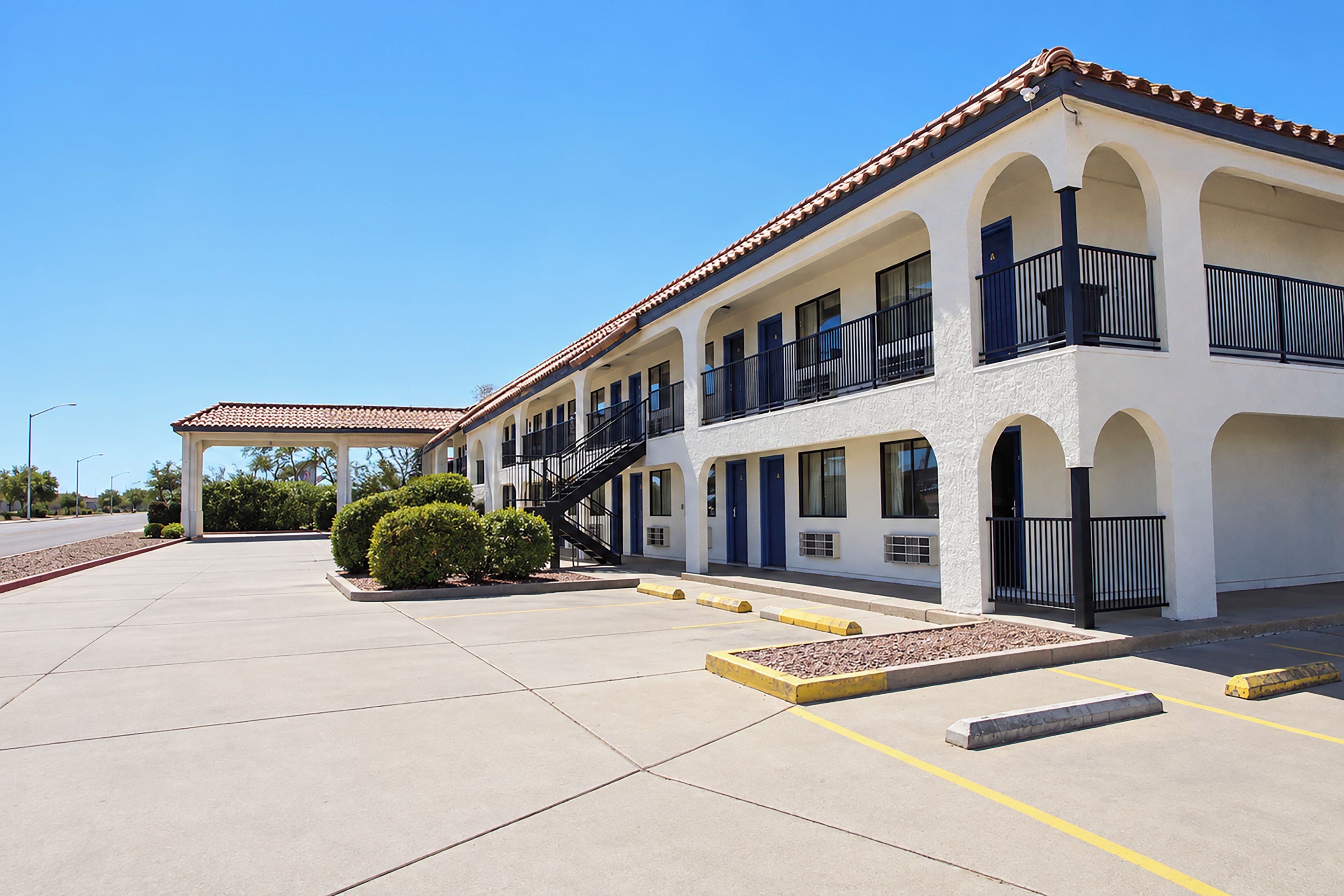 A multi-story hotel with a covered parking area and a clear sky.