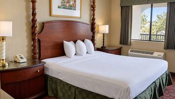 A hotel room with a large bed, two bedside tables with lamps, a window with curtains, and a radiator.