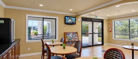 A dining area with a television, a bookshelf, and a door leading outside.