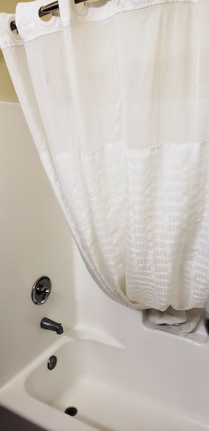 A white bathtub with a shower curtain, a faucet, and a drain. - Kingman Inn Route 66 I-40 (Kingman)