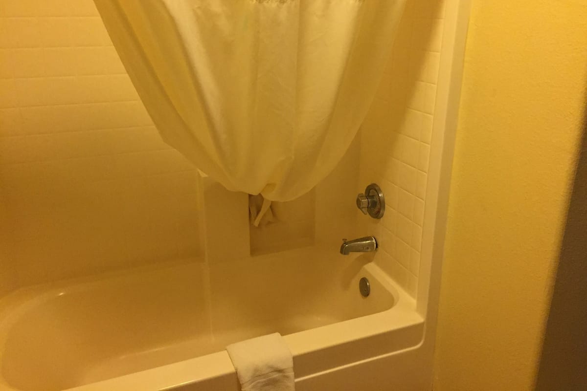 A bathtub with a shower curtain, a towel hanging on the side, and a faucet.