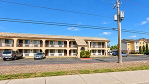 A motel with multiple balconies, a parking lot, and a utility pole. - Kingman Inn Route 66 I-40 (Kingman)