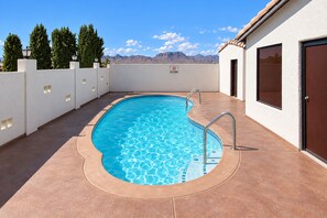 A swimming pool with a no swimming sign, surrounded by a white wall and a door on the right. - Kingman Inn Route 66 I-40 (Kingman)