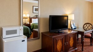 A hotel room with a bed, a television on a wooden cabinet, a microwave, and a desk with a lamp. - Kingman Inn Route 66 I-40 (Kingman)