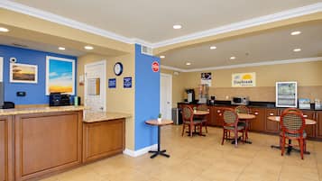 A hotel breakfast area with a counter, chairs, a clock, and a Daybreak sign.