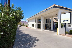 A gas station with a clear sky, a red carpet leading to the entrance, and a sign indicating the direction to enter. - Kingman Inn Route 66 I-40 (Kingman)