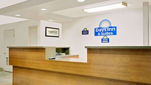 Mostrador de recepción en Days Inn & Suites con un cuadro enmarcado en la pared y un letrero que indica que hay un gerente de turno.