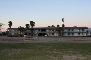 A motel with a flat roof, multiple balconies, and a parking lot. - Days Inn & Suites by Wyndham Needles (Needles)