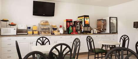 Una cocina moderna con gabinetes blancos, un televisor de pantalla plana y una estación de café.