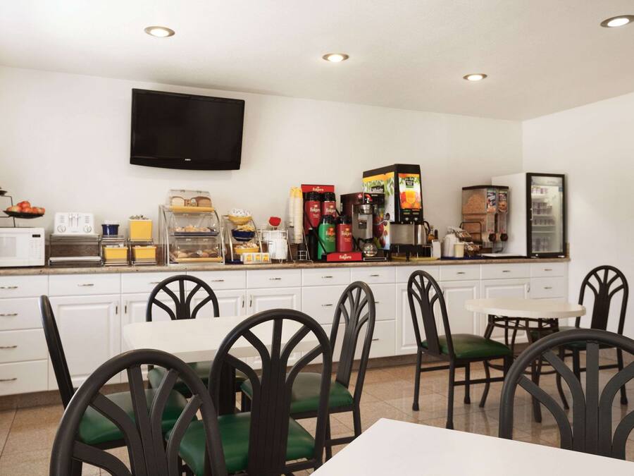 A modern kitchen with white cabinets, a flat-screen TV, and a coffee station.