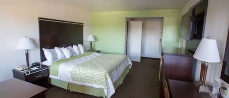 Habitación de hotel con cama, mesitas de noche, escritorio, silla, cómoda y espejo.