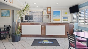 A Days Inn lobby with a reception desk, a television, framed artwork, and a potted plant. - Days Inn by Wyndham Lost Hills (Lost Hills)