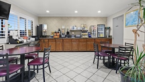 A restaurant with a tiled floor, wooden cabinets, and a counter with various food items and appliances. - Days Inn by Wyndham Lost Hills (Lost Hills)