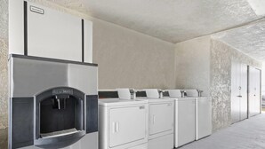 A laundry facility with a water dispenser and multiple washing machines. - Days Inn by Wyndham Lost Hills (Lost Hills)