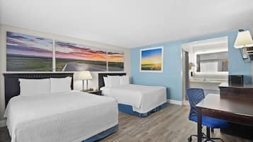 Habitación de hotel con dos camas, un escritorio, una silla y un ventanal grande.