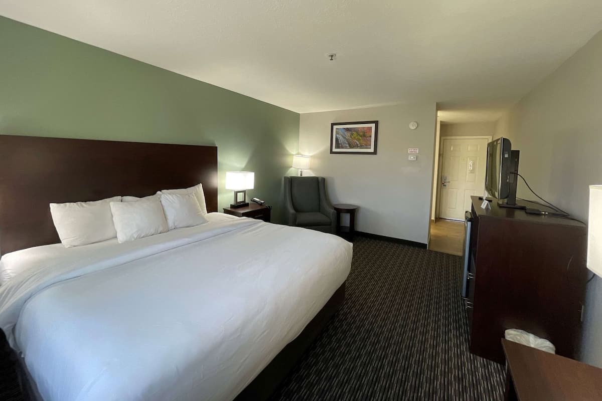 Habitación de hotel con una cama grande, un escritorio con computadora, una silla y un televisor.