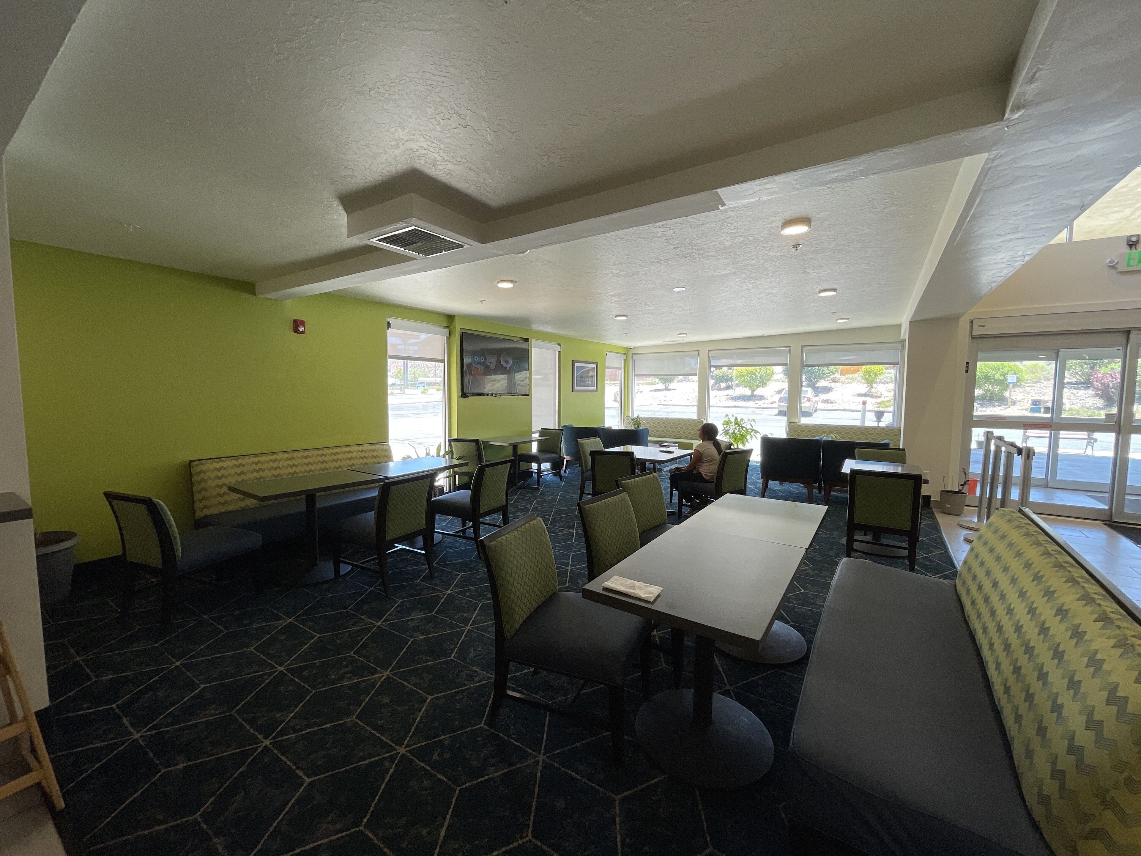 Un restaurant avec des banquettes et des tables, des murs verts et un sol carrelé.