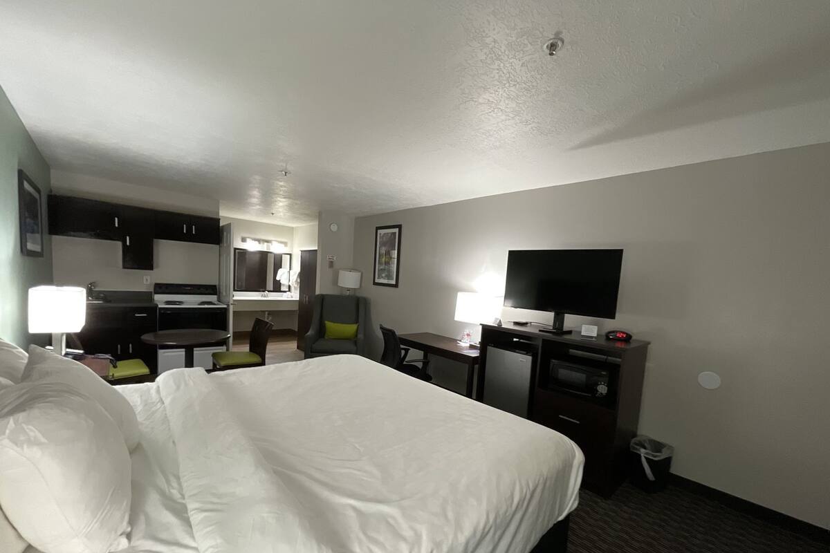 Habitación de hotel con cama, escritorio, televisión y kitchenette.