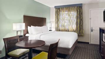 A hotel room with a large bed, two bedside lamps, a desk with a chair, and a television.