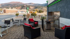 Een terras buiten met rieten meubilair en uitzicht op bergen.