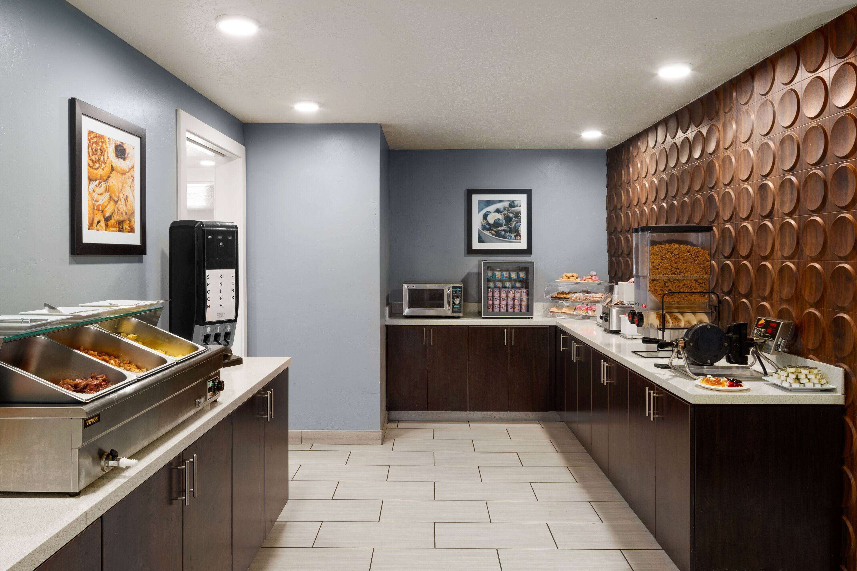 A modern kitchen with a buffet setup, microwave, and coffee machine.