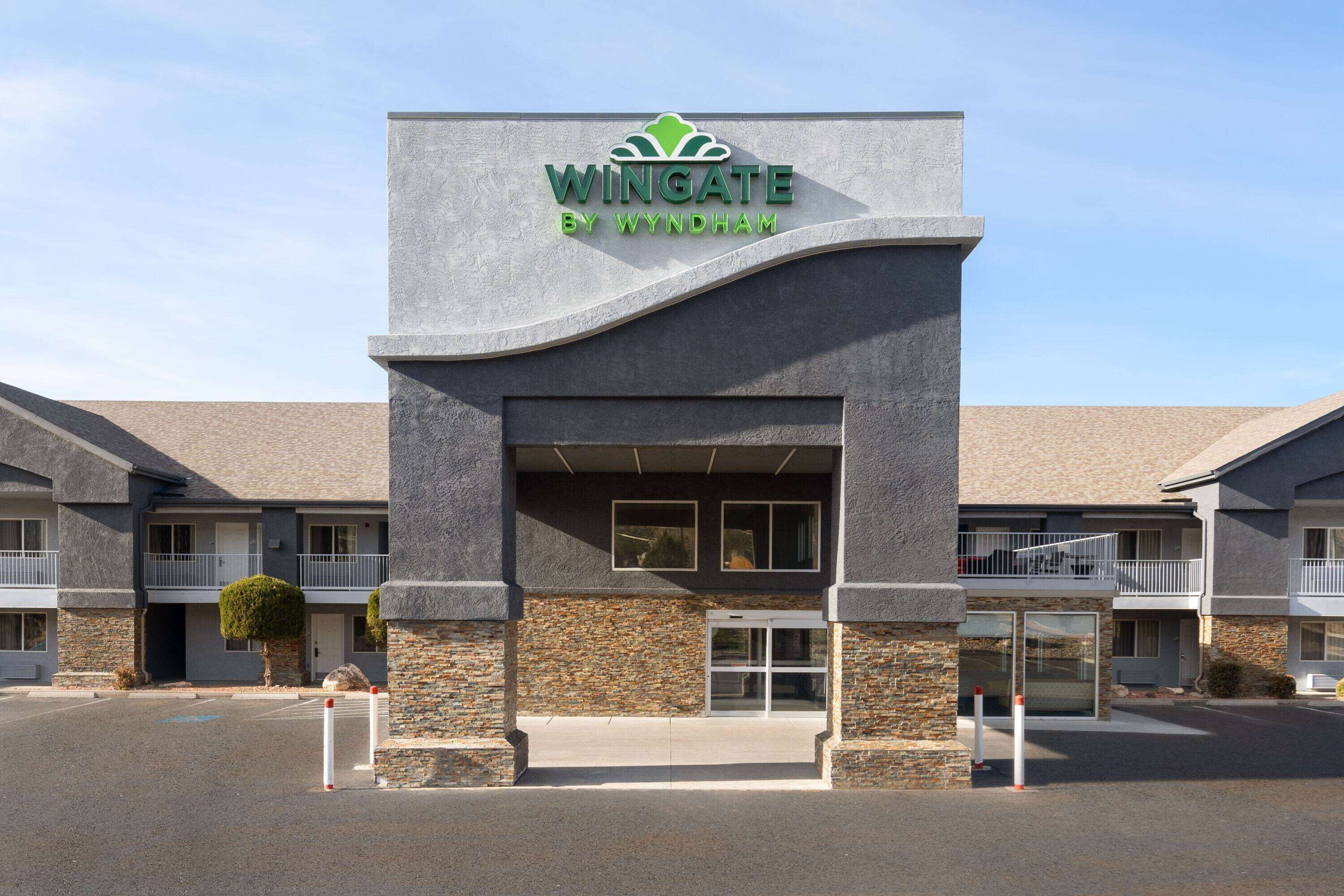 A Wingate by Wyndham hotel with a stone facade, multiple balconies, and a clear entrance.