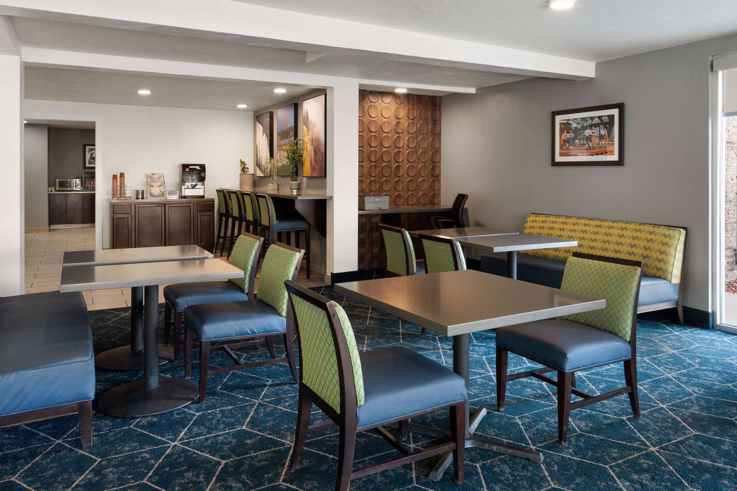 A hotel lobby with a reception desk, seating area, and a coffee station.