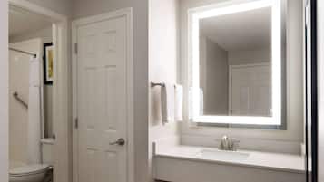 A bathroom with a white toilet, a sink with a mirror above it, and a door.
