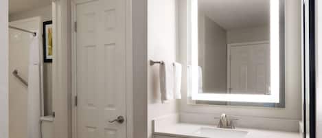 Un baño con inodoro blanco, lavamanos y espejo superior, y una puerta.