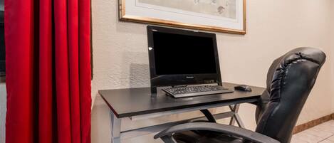 A desk with a laptop, a mouse, and a black leather chair.