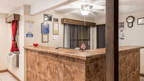 A reception area with a marble counter, a ceiling fan, and various informational signs.