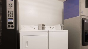 A laundry room with two white washers and dryers, a Whirlpool brand dryer, and a control panel with a digital display.