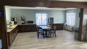 A modern kitchen with a dining area, equipped with a coffee machine, microwave, and a flat-screen TV.