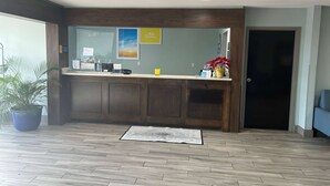 A reception area with a wooden counter, a large potted plant, and a framed picture on the wall.