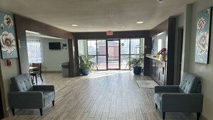 A reception area with two grey armchairs, a reception desk, potted plants, and artwork on the walls.