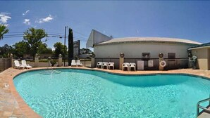 A swimming pool with lounge chairs and a building in the background.