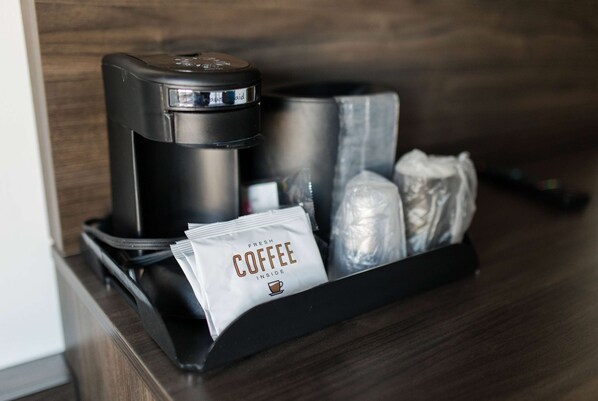 A coffee maker, a coffee pod, and a cup of coffee on a tray.