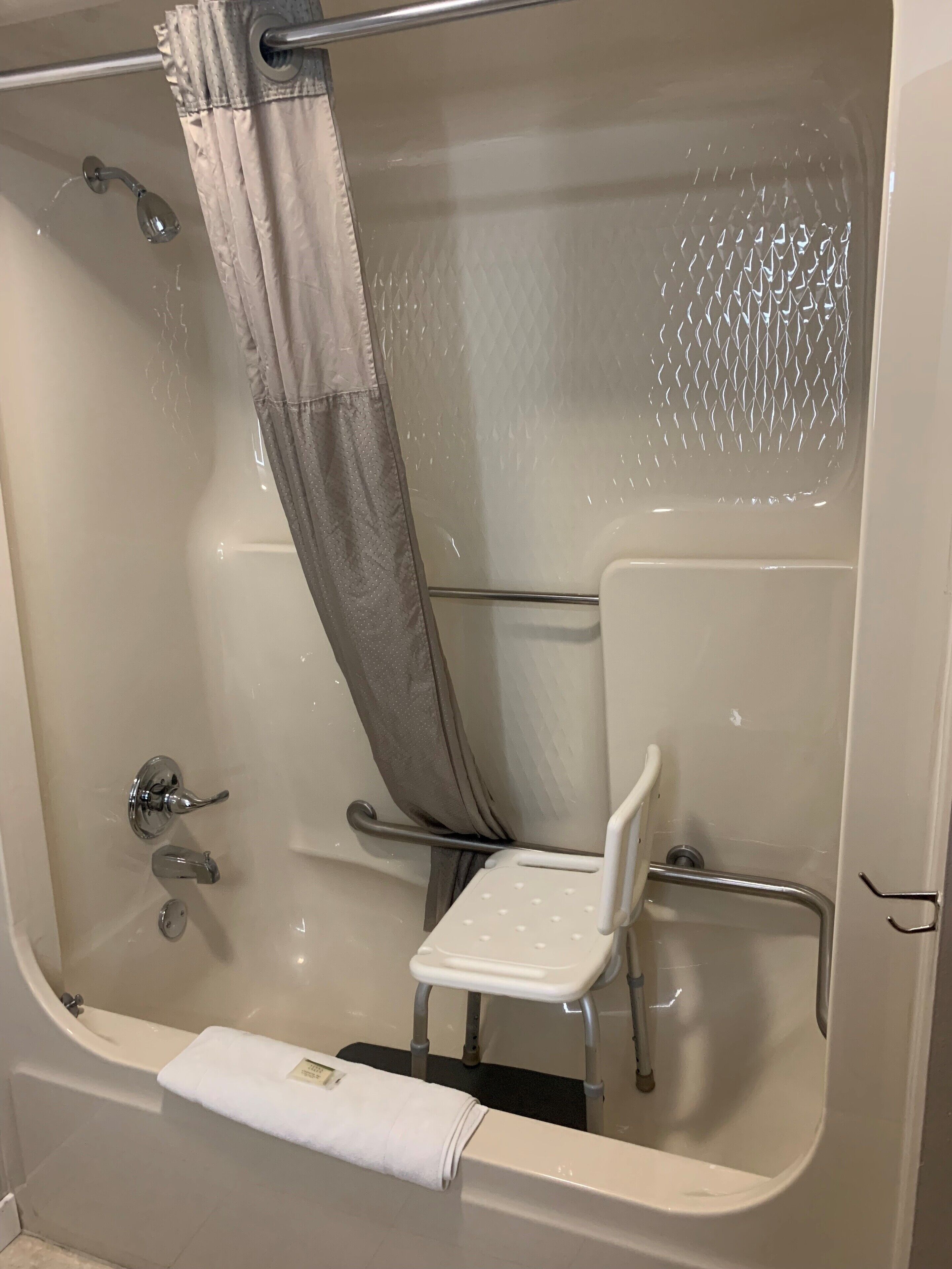 A bathtub with a showerhead, a towel rack, and a grab bar.
