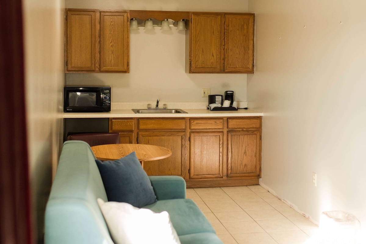 Una cocina compacta con armarios de madera, microondas, cafetera y una pequeña mesa de comedor.