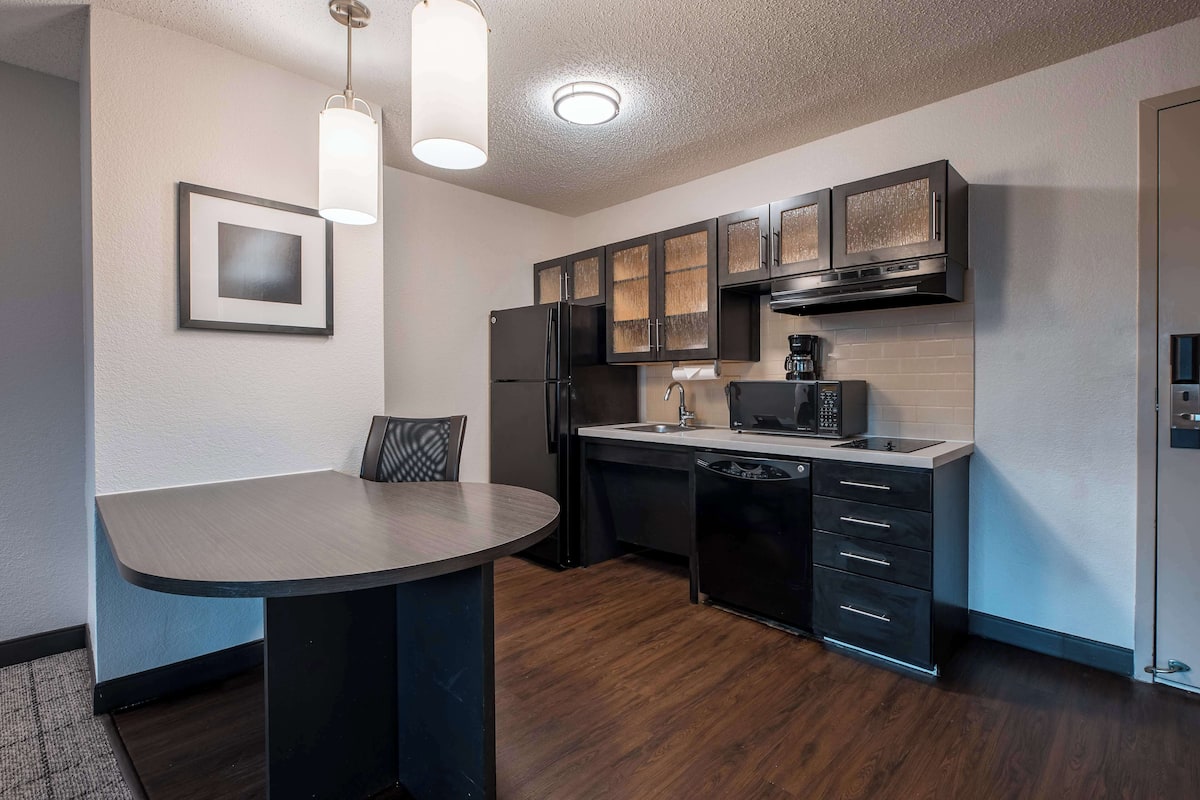 A modern kitchen with dark cabinetry, a built-in dishwasher, and a round dining table.