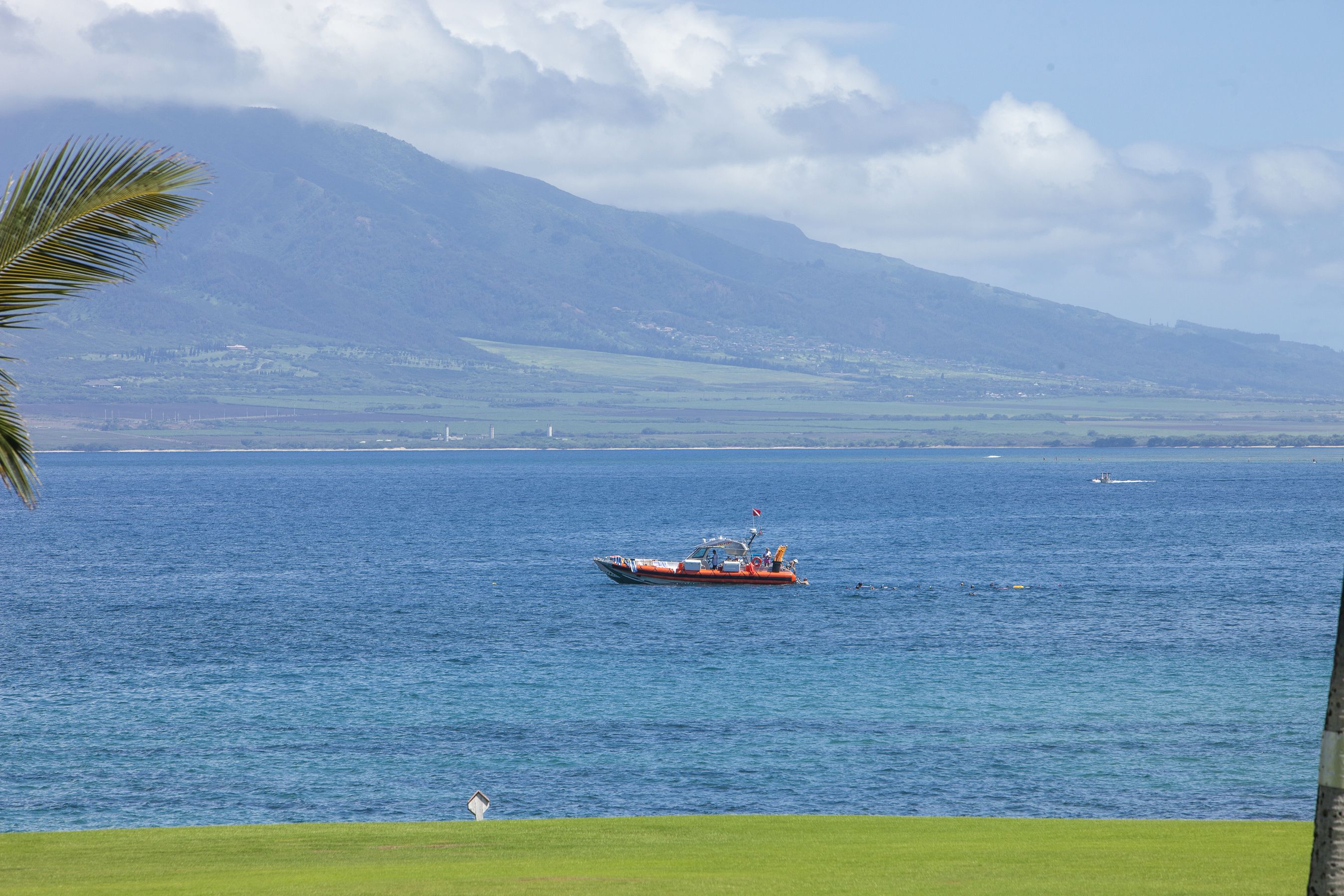 A boat on a calm sea with a mountain in the background.