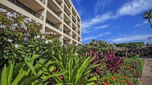 Un hôtel à plusieurs étages doté de balcons, entouré d’une végétation luxuriante et de plantes en fleurs.