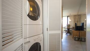 A laundry area with stacked washers and dryers, a dining area with a table and chairs, and a kitchen with cabinets and a sink.